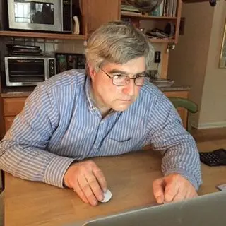 A man sitting at the table looking at his laptop.